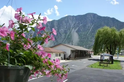 a building with pink flowers in front of a mountain at Elks Motel in Keremeos