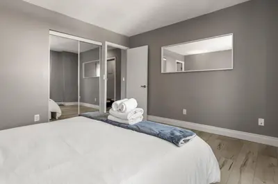 a bedroom with a white bed and a mirror at Downtown Apartment with Underground Parking, Netflix, Fully Equipped Kitchen, Walk to 17th Ave, Sleeps 4, Perfect for Foodies and Tourists in Calgary