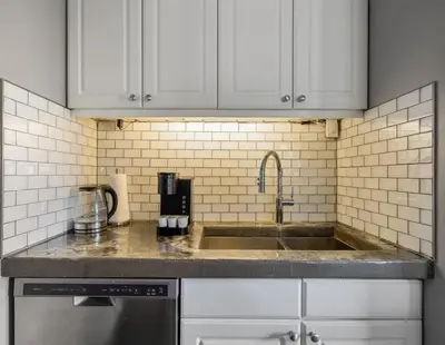 a kitchen with white cabinets and a sink at Downtown Apartment with Underground Parking, Netflix, Fully Equipped Kitchen, Walk to 17th Ave, Sleeps 4, Perfect for Foodies and Tourists in Calgary