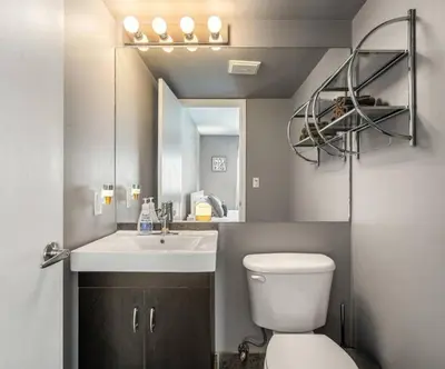 a bathroom with a sink and a toilet and a mirror at Downtown Apartment with Underground Parking, Netflix, Fully Equipped Kitchen, Walk to 17th Ave, Sleeps 4, Perfect for Foodies and Tourists in Calgary