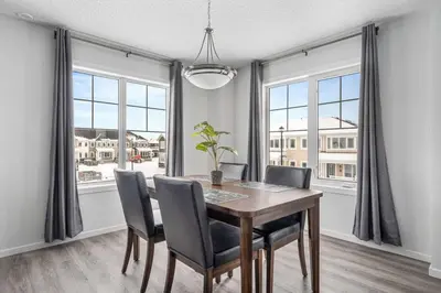 a dining room with a table and chairs and windows at 4 Bedroom Town Home with Garage Parking, Fast WiFi, Smart TV with Netflix, Fully Equipped Kitchen, Sleeps 10, Ideal for Families in Airdrie