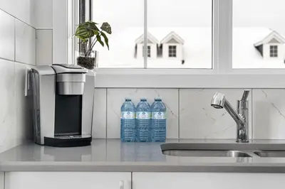 a kitchen with two bottles of water on a counter at 4 Bedroom Town Home with Garage Parking, Fast WiFi, Smart TV with Netflix, Fully Equipped Kitchen, Sleeps 10, Ideal for Families in Airdrie