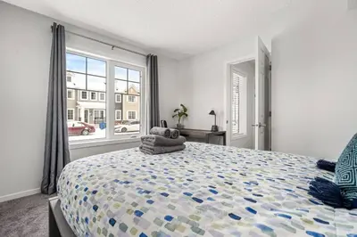 a bedroom with a large bed and a window at 4 Bedroom Town Home with Garage Parking, Fast WiFi, Smart TV with Netflix, Fully Equipped Kitchen, Sleeps 10, Ideal for Families in Airdrie