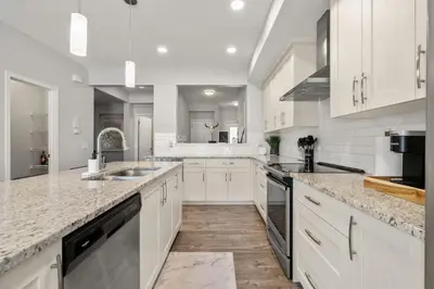 a kitchen with white cabinets and marble counter tops at Top Rated Luxury House with Central AC, Double Garage Parking, 2 Kitchens, 5 Bedrooms & More! in Balzac