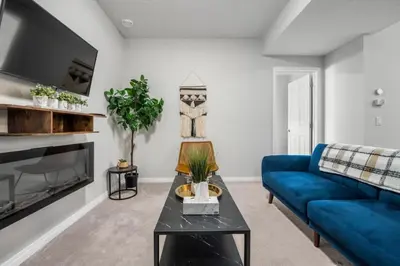a living room with a blue couch and a tv at Top Rated Luxury House with Central AC, Double Garage Parking, 2 Kitchens, 5 Bedrooms & More! in Balzac