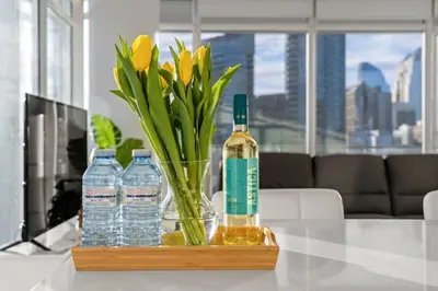 a glass vase with a bottle of water and flowers at Luxury Apartment on the 9th Floor near Stampede, Complimentary Wine, 2 Car UG Parking in Calgary