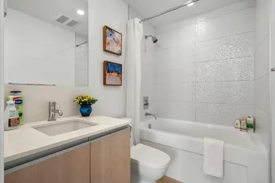 a bathroom with a sink and a toilet and a tub at Luxury Apartment on the 9th Floor near Stampede, Complimentary Wine, 2 Car UG Parking in Calgary