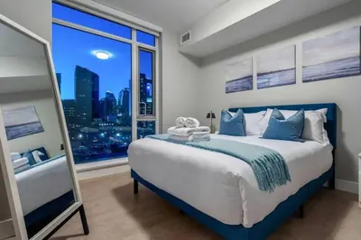 a bedroom with a large bed with a large window at Luxury Apartment on the 9th Floor near Stampede, Complimentary Wine, 2 Car UG Parking in Calgary