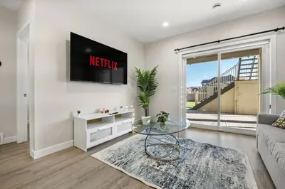 a living room with a couch and a tv on a wall at Private Suite with Queen Bed, Queen Sofa Bed, Netflix, Patio, Sleeps 4 in Calgary