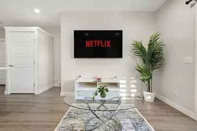 a living room with a table and a tv on the wall at Private Suite with Queen Bed, Queen Sofa Bed, Netflix, Patio, Sleeps 4 in Calgary