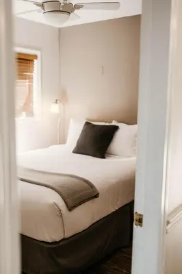 a bedroom with a bed with white sheets and a ceiling at Page's Inn on Silva Bay in Gabriola