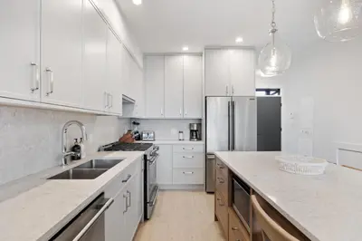 a kitchen with white cabinets and a stainless steel refrigerator at Coastal Haven at THE BEACH HOUSE in Campbell River