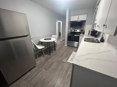 a kitchen with a refrigerator and a table in it at Cute Highland Park Upper B Unit in Calgary