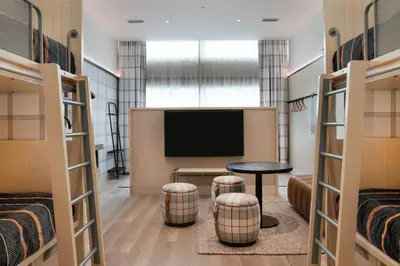a room with a tv and a table and two beds at Moxy Banff in Banff