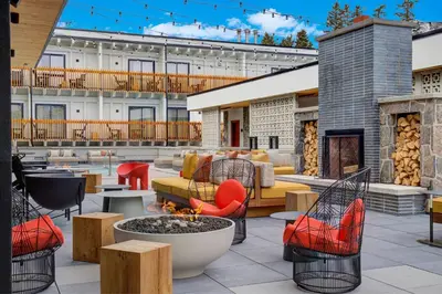 a patio with chairs and tables and a fire pit at Moxy Banff in Banff