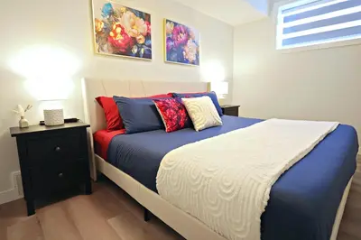 a bedroom with a bed with blue and red pillows at Downtown Suite King Beds,Long Stays,Disney+ in Edmonton