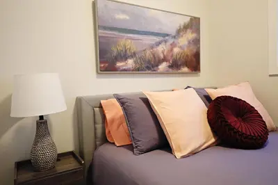 a bedroom with a couch with pillows and a painting at Central 3 Queen Beds, AC, Double Garage, Disney in Edmonton