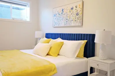 a bedroom with a bed with yellow and white pillows at Central Suite King Beds,Long Stays,Disney+ in Edmonton