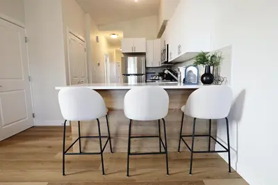 a kitchen with three white stools at a kitchen counter at Central 5 Bedroom, AC, Rogers, Commonwealth, EXPO in Edmonton