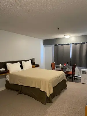 a bedroom with a bed and a table and chairs at Nechako Valley Inn in Vanderhoof