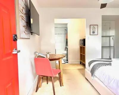 a room with a table and a bed and a red door at 'Canyon Heights' Retreat (Grouse Mountain) in North Vancouver