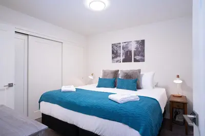 a white bedroom with a large bed with blue sheets at Peak Paradise by Revelstoke Vacations in Revelstoke