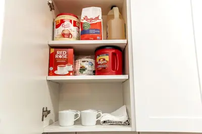 a kitchen pantry with cups and food items on shelves at Chic Suite - Long Stays - King Bed - Fireplace & WiFi in Edmonton