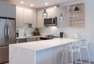 a kitchen with white cabinets and a counter with stools at The Stoke Stopover - Revelstoke Condo with Hot Tub in Revelstoke