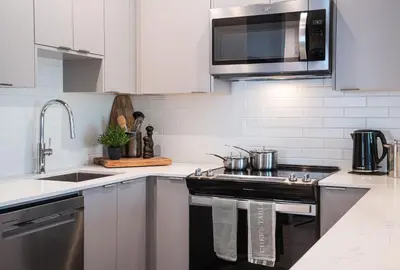 a white kitchen with a stove and a microwave at The Stoke Stopover - Revelstoke Condo with Hot Tub in Revelstoke