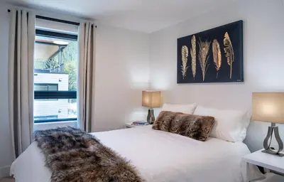 a bedroom with a white bed and a window at The Stoke Stopover - Revelstoke Condo with Hot Tub in Revelstoke