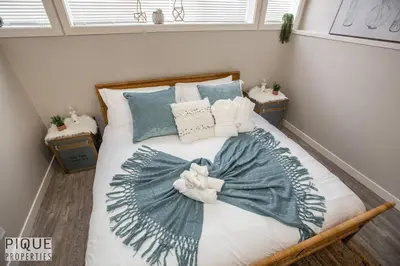 a bed with blue and white sheets and pillows at Boho Suite - Long Stays - King Bed - Fireplace & WiFi in Edmonton