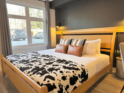 a bedroom with a bed with a black and white blanket at W118 NEW! Central Canmore- Light Industrial Hotel Room in Canmore