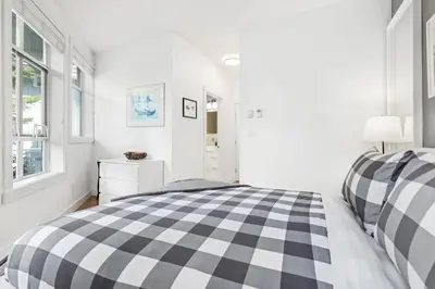 a white bedroom with a black and white checkered bed at 2BR in Granite Court, Village Location, Gas Fireplace, Mudroom, Secure Parking in Whistler