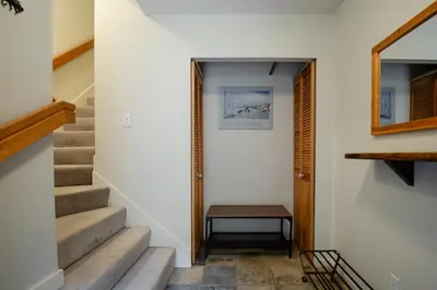 a hallway with stairs and a table next to a door at 2BR in Valhalla, Whistler Village, Complex Hot Tub, Gas Fireplace, Parking, Gondola Shuttle in Whistler