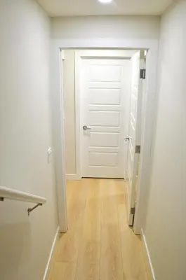 an empty hallway with a white door and a wooden floor at Secondary Suite, Separate Entrance NW Calgary in Calgary