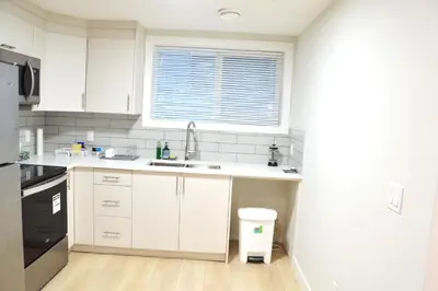 a kitchen with white cabinets and a sink and a window at Secondary Suite, Separate Entrance NW Calgary in Calgary