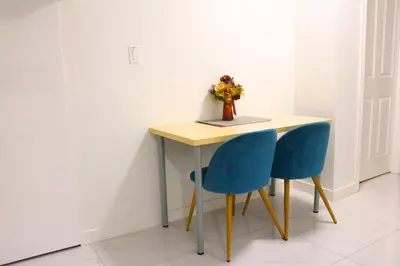 a table with two blue chairs and a vase with flowers at Pristine 3 Beds 2 Washroom Guest Suite in Surrey