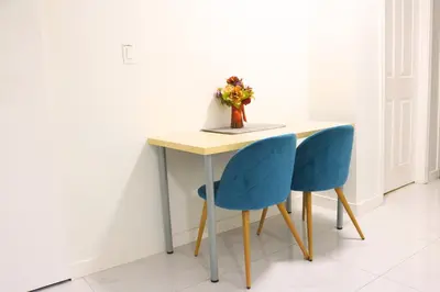 a table with two blue chairs and a vase of flowers at Pristine 3 Beds 2 Washroom Guest Suite in Surrey