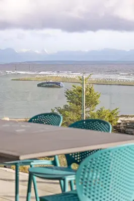 a table and chairs with a view of the ocean at Beachfront Luxury Suite #15 at THE BEACH HOUSE in Campbell River