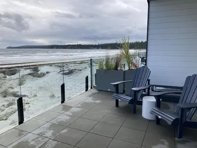 a porch with two chairs and a view of the beach at Beachfront Luxury Suite #15 at THE BEACH HOUSE in Campbell River