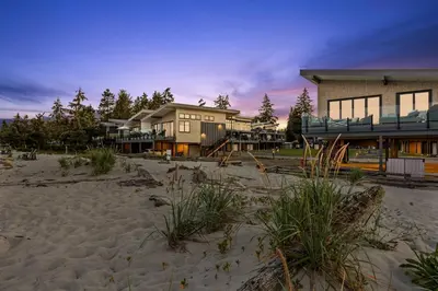 a large house on the beach with a building at Beachfront Luxury Suite #15 at THE BEACH HOUSE in Campbell River