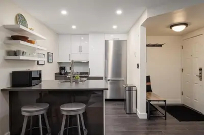 a kitchen with a counter with stools and a refrigerator at 2BR in The Gables, Prime Location, Steam Shower, Heated Flooring, Wood Burning Fireplace in Whistler