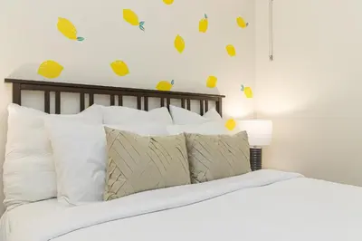 a bed with white pillows and yellow butterflies on the wall at Be Vogue In Old Town Victoria in Victoria