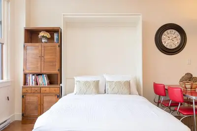 a bedroom with a bed and a clock on the wall at Be Vogue In Old Town Victoria in Victoria