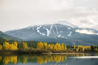 a mountain reflecting in a lake with trees and snow at 3BR and Den in Gleneagle, Wood Burning Fireplace, Heated Flooring, Secure Parking in Whistler