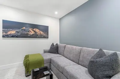 a living room with a couch and a picture of a mountain at 3BR and Den in Gleneagle, Wood Burning Fireplace, Heated Flooring, Secure Parking in Whistler