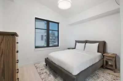a white bedroom with a bed and a window at Beachfront Luxury Suite #21 at THE BEACH HOUSE in Campbell River