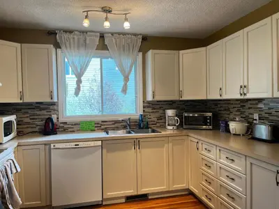 a kitchen with white cabinets and a window at Beddington masteroom close airport! in Calgary