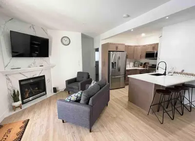 a living room with a couch and a kitchen with a fireplace at Relaxing 3 bedroom suite, near Silver Star Resort in Vernon