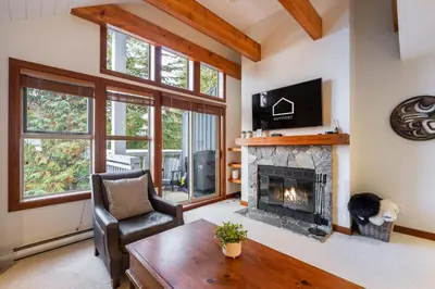 a living room with a fireplace and a chair at Treeline by Outpost Whistler in Whistler